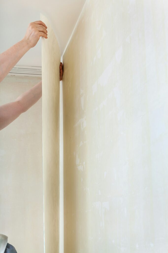 wallpapering on clean wall in room